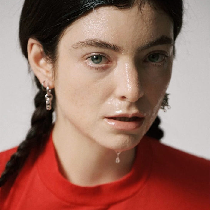 Editorial portrait in a red top with braided hair and dewy skin, with full, natural brows by Maggie Moon
