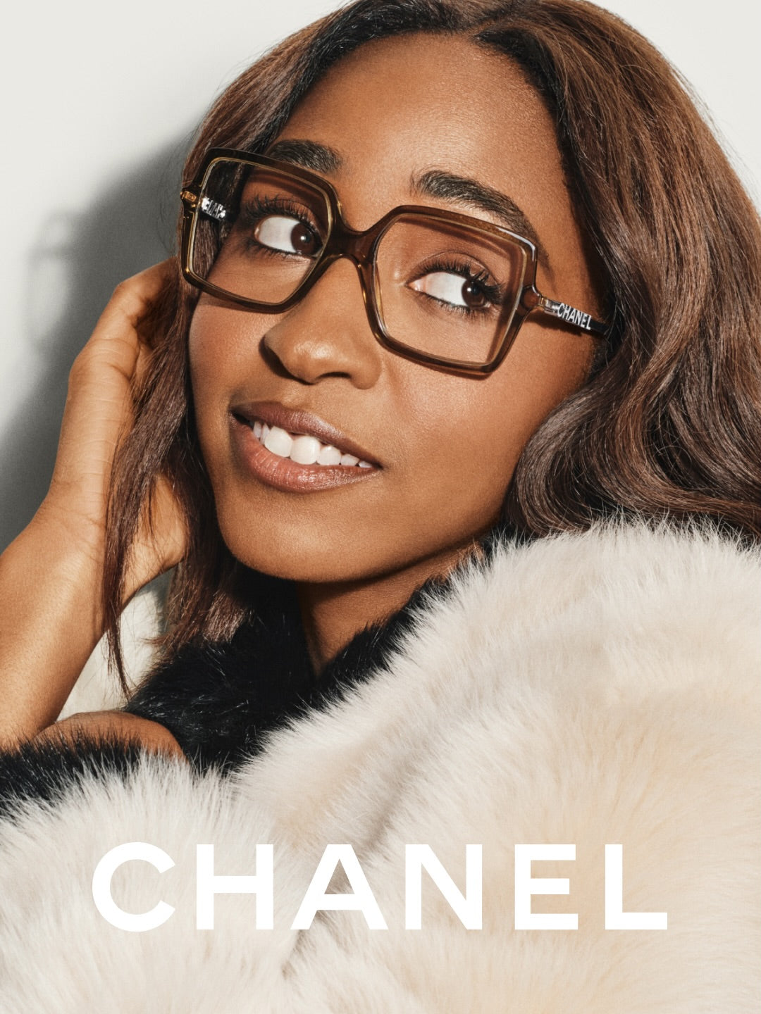 Chanel eyewear campaign portrait in square tortoiseshell glasses and cream fur, with full, softly arched brows by Maggie Moon