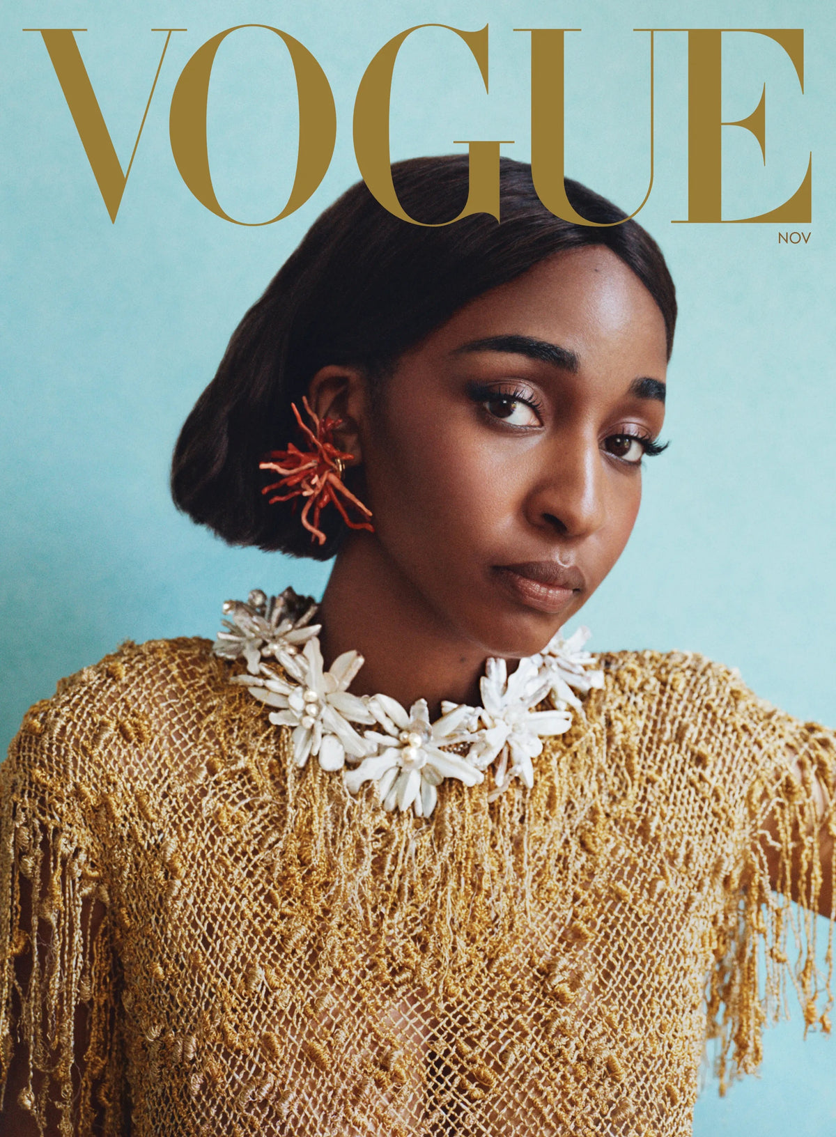 Vogue November cover in a gold crochet top and white flower collar, with defined, arched brows by Maggie Moon